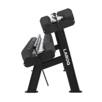 Râtelier noir à deux niveaux rempli d'haltères hexagonaux noirs alignés sur des barres, structure tubulaire inclinée avec pieds évasés et supports latéraux visibles sur fond gris uni.